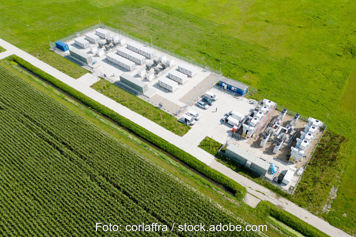Luftbild zeigt einen großen Batteriespeicher mit mehreren Containern an einem Weg inmitten von Wiesen. Symbolbild für Flächenpooling.