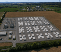 Luftaufnahme einer Visualisierung des geplanten Batteriespeicherprojekts in Lamspringe. Zu sehen ist ein großer Batteriespeicher mit zahlreichen Containerreihen, Umspannwerk und Netzanschluss auf einer eingezäunten Fläche zwischen landwirtschaftlichen Feldern.