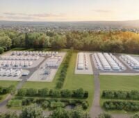 Batteriespeicerhprojekt auf der grünen Wiese mit Bäumen im Hintergrund vor dem Horizont. Aufgenommen aus der Vogelperspektive.