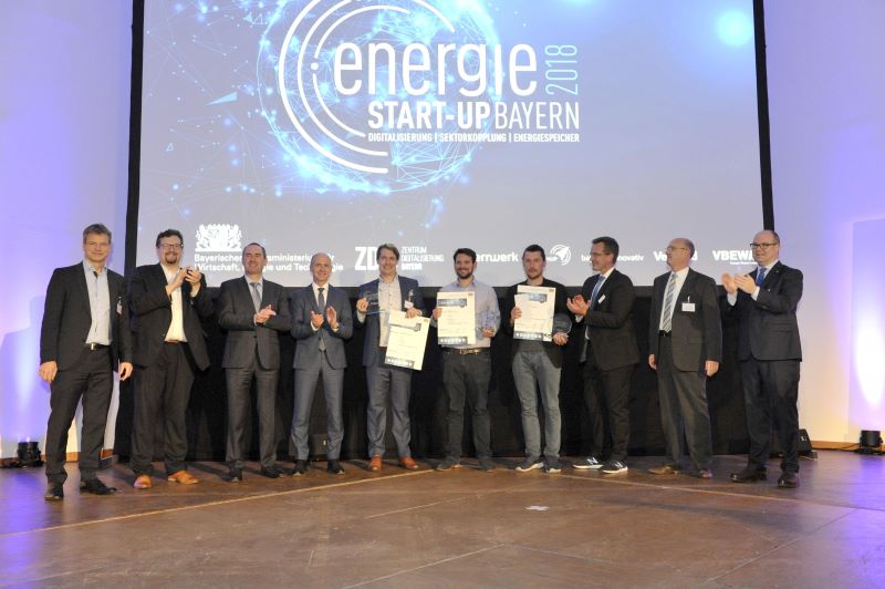 Auf einer Bühne stehen zehn Personen und präsentieren Urkunden vom Byrischen Energiuepreis 2018 für Start-Ups.