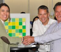 Zwei Männer und eine Frau schütteln sich die Hände - Übernahme von Ribeiro Solar in Brasilien durch Baywa r.e.