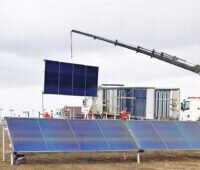 Großflächen-Solarthermie-Kollektoren der Marke Enercon werden mit einem Kranwagen auf der Baustelle vom LKW abgeladen und direkt montiert.