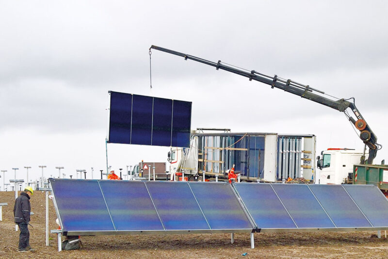 Großflächen-Solarthermie-Kollektoren der Marke Enercon werden mit einem Kranwagen auf der Baustelle vom LKW abgeladen und direkt montiert.