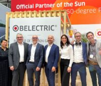 Sieben Frauen und Männer vor einem Messestand von Belectric.