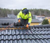 Ein Monteur installiert auf einem Dach Solarziegel, denen man die Solartechnik nicht ansieht.