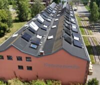 Alte Industriehalle mit PV-Modulen auf dem M-förmigen Dach.