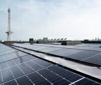PV-Anlage auf Flachdach, im Hintergrund ein Turm.