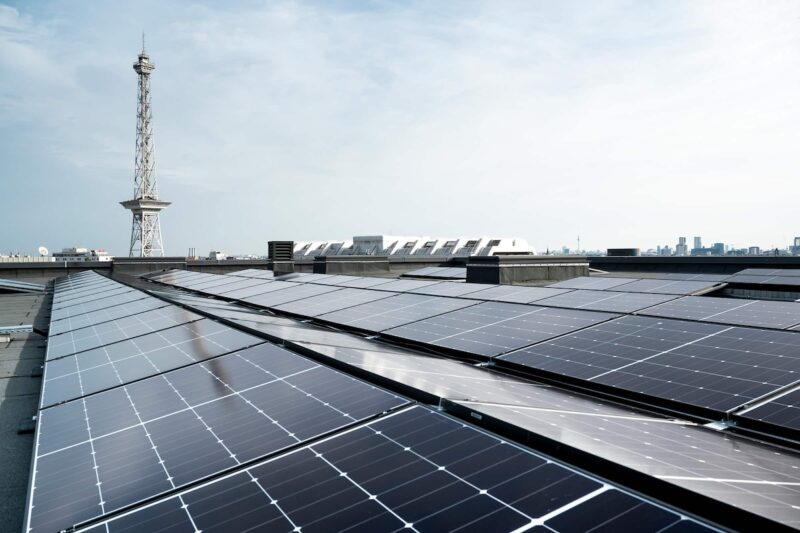 PV-Anlage auf Flachdach, im Hintergrund ein Turm.