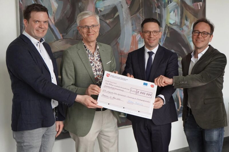 Vier Personen halten erfreut einen überdimensionierten Check über sechgs Millionen Euro in die Kamera.