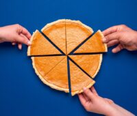 Kuchen in Stücken, drei Hände nehmen sich je ein Stück - Symbol für Beteiligung von Kommunen an Energiewende-Projekten.