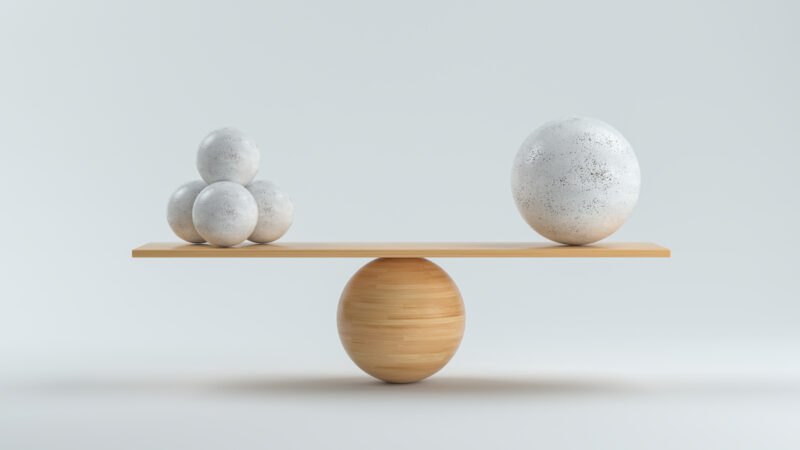 Waage mit Steinkugeln im Gleichgewicht als Symbol für einen ausgeglichenen Bilanzkreis in der Energiewende.