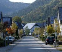 Dörfliche Straße mit Einfamilienhäusern udn PV-Anlagen.