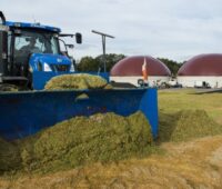 Zu sehen ist ein Traktor vor einer Biogasanlage.Die Ausschreibungsrunde für Biomasse ist unterzeichnet.
