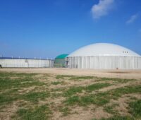 Eine Biogasanlage mit Fermenter unter blauem Himmel.