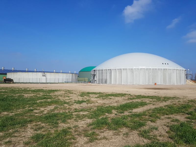 Eine Biogasanlage mit Fermenter unter blauem Himmel.