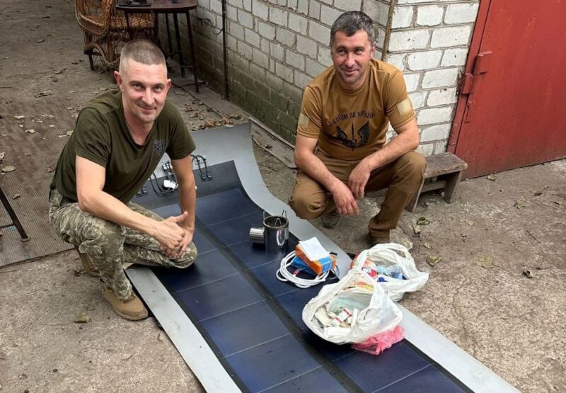 Im Bild zwei Männer mit einer der Solar-Dachbahnen, die für die Ukraine im Krieg gegen Russland sehr hilfreich sind.