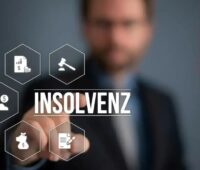 Ein Mann - unscharf - tippt mit dem Finger auf den Schriftzug Insolvenz als Overlay im Vordergrund.