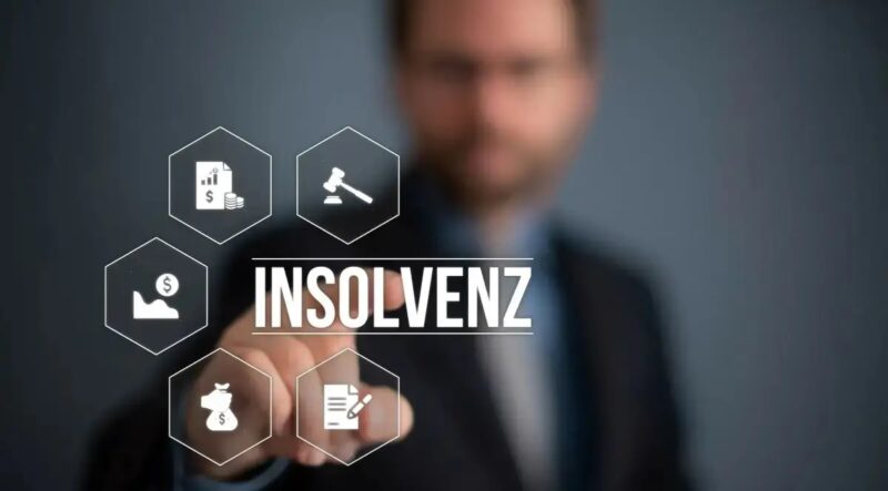 Ein Mann - unscharf - tippt mit dem Finger auf den Schriftzug Insolvenz als Overlay im Vordergrund.