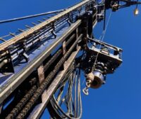 Bohrturm vor blauem Himmel aus Froschperspektive - Bohrgeräte und Fachkräfte gehören zu den kritischen Faktoren für die Geothermie