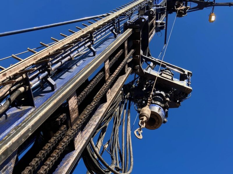 Bohrturm vor blauem Himmel aus Froschperspektive - Bohrgeräte und Fachkräfte gehören zu den kritischen Faktoren für die Geothermie