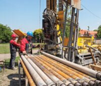 Bohrgestänge im Vordergrund vor einer Brunnen-Bohrmaschine
