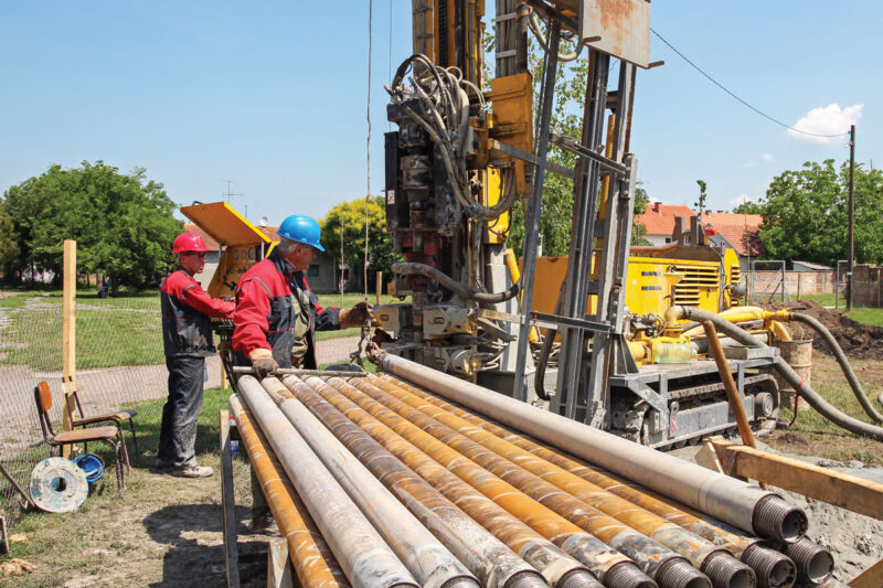 Bohrgestänge im Vordergrund vor einer Brunnen-Bohrmaschine