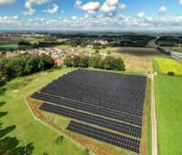 Luftbild einer Freiflächensolaranlage im grünen Umfeld.