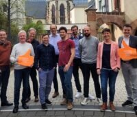 10 Vertreter:innen der Bürgerwerke vor einer historischen Kirche.
