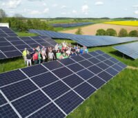 Menschentraube in einem Bürgersolarpark aus der Luft fotografiert