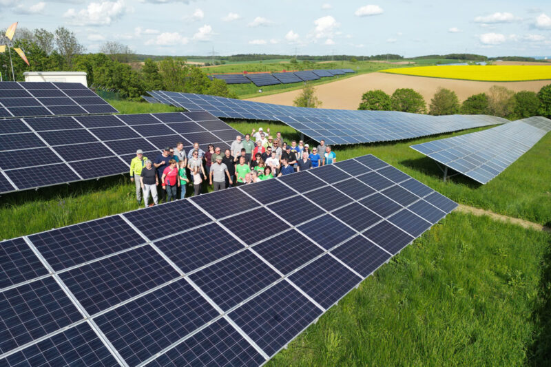 Menschentraube in einem Bürgersolarpark aus der Luft fotografiert