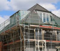 Zu sehen ist ein Haus mit Gerüst. Der Bund will mit der Teilung der CO2-Kosten zwischen Vermietern und Mietern die Sanierung voranbringen.