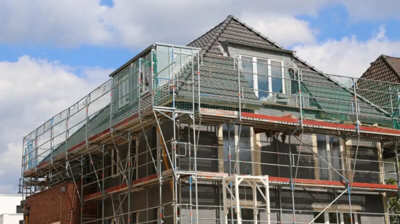 Zu sehen ist ein Haus mit Gerüst. Der Bund will mit der Teilung der CO2-Kosten zwischen Vermietern und Mietern die Sanierung voranbringen.