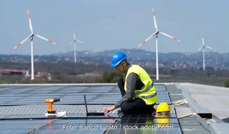 Ein Monteur auf dem Dach baut Solarmodule ein, neue Ausschreibungen für Windenergie und Photovoltaik auf Gebäuden und Lärmschutzwänden im Februar 2025.