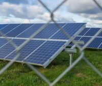Zu sehen ist eine eingezäunte PV-Großanlage als Symbol für die Verschleppung der Ausbaupfade für Photovoltaik und Windenergie durch die Bundesregierung.