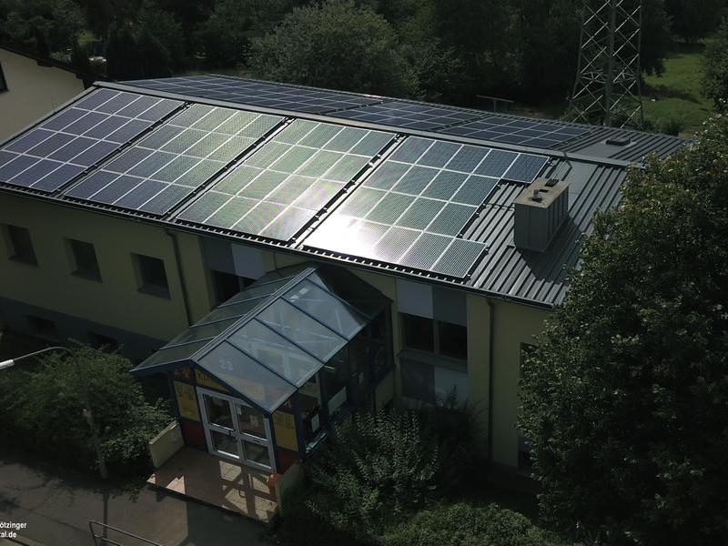 Blick auf das Dach einer Kita mit Solarmodulen.