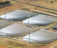 Blick aus der Luft auf fünf rechteckige Felder von Spiegeln, die auf jeweils einen Turm ausgerichtet sind. CSP-Kraftwerk von Vast Solar in Australien.