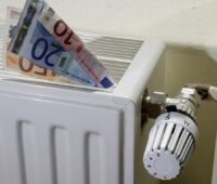 Zu sehen sind Geldscheine im Heizkörper als eine symbolische Darstellung für die Ersparnis durch die Modernisierung mit Wärmepumpe und Photovoltaik.