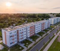 Sonnenuntergang über einer Wohnanlage in Landschaft mit Photovoltaik auf dem Dach
