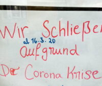 Ein handscvhriftliches Schild in einer FEnsterscheibe informiert, dass wegen Corona geschlossen ist.