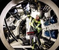 Ein Dekra-Prüfer bei einer Windenergieanlagen-Inspektion, die Prüforganisation stellt auf der Messe Husum Wind 2025 aus.