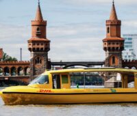 Ein gelbes Solarboot mit DHL-Logo auf der Spree.