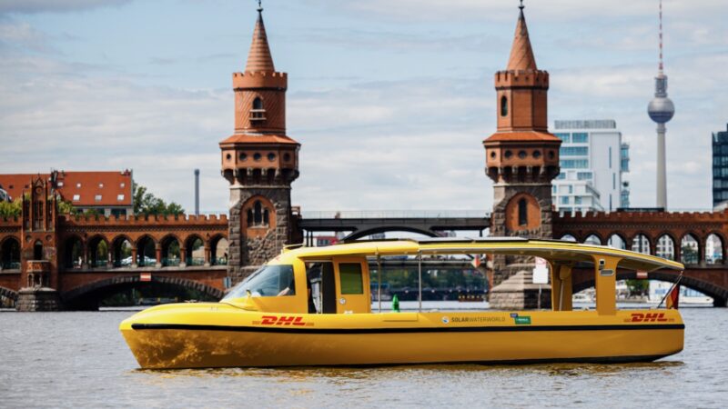 Ein gelbes Solarboot mit DHL-Logo auf der Spree.