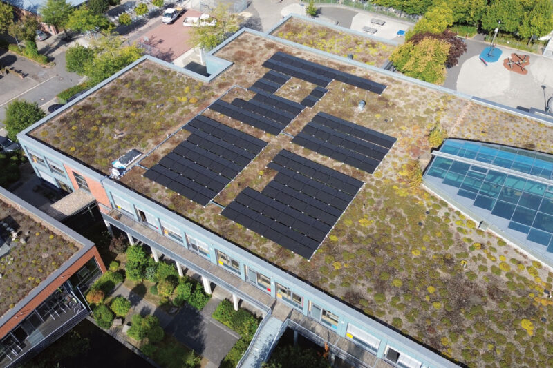Gründach mit Photovoltaikanlage auf einem Schuldach in Hückelhoven - im Innern des Gebäudes befindet sich ein Batteriespeicher.