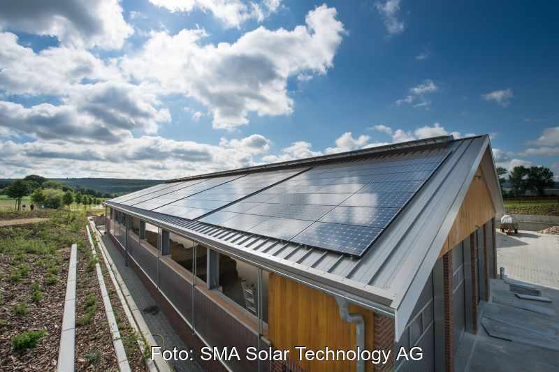 Eine Solardachanlage unter blauem Himmel mit Sonne und Wolken.