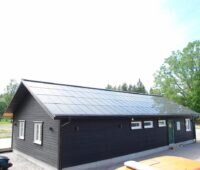 Zu sehen ist ein Holzhaus in Schweden, das dachintegrierte Photovoltaik-Module trägt.