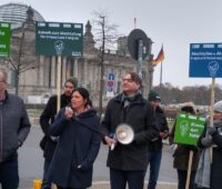 Menschen mit Schildern und Megafon - Demonstration gegen Erlösabschöpfung in der Bioenergie-Branche