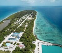 Zu sehen sind vernetzte Photovoltaik-Microgrids auf einer Luftaufnahme einer Insel der Malediven im blauen Ozean.