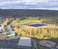 Eine große Solarthermieanlage umgeben von Feldern am französischen Fluss Dordogne. Auf der anderen Seite des Flusses ein Industriebetrieb.