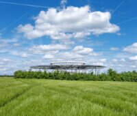 Drehfunkfeuer inmitten grünen Getreides vor blauem Himmel.