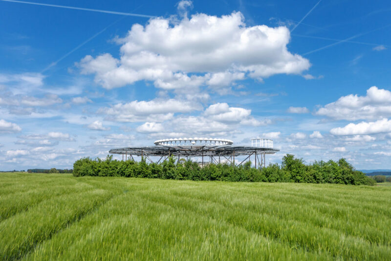 Drehfunkfeuer inmitten grünen Getreides vor blauem Himmel.